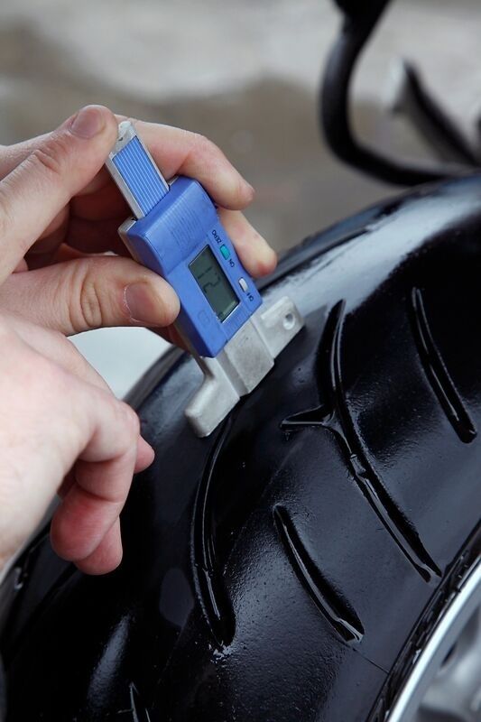 Digital caliper measuring tread depth on a motorcycle tire